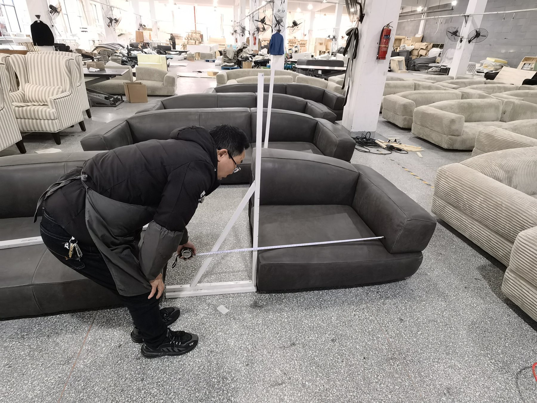 Inspector checking sofa details in factory showroom area